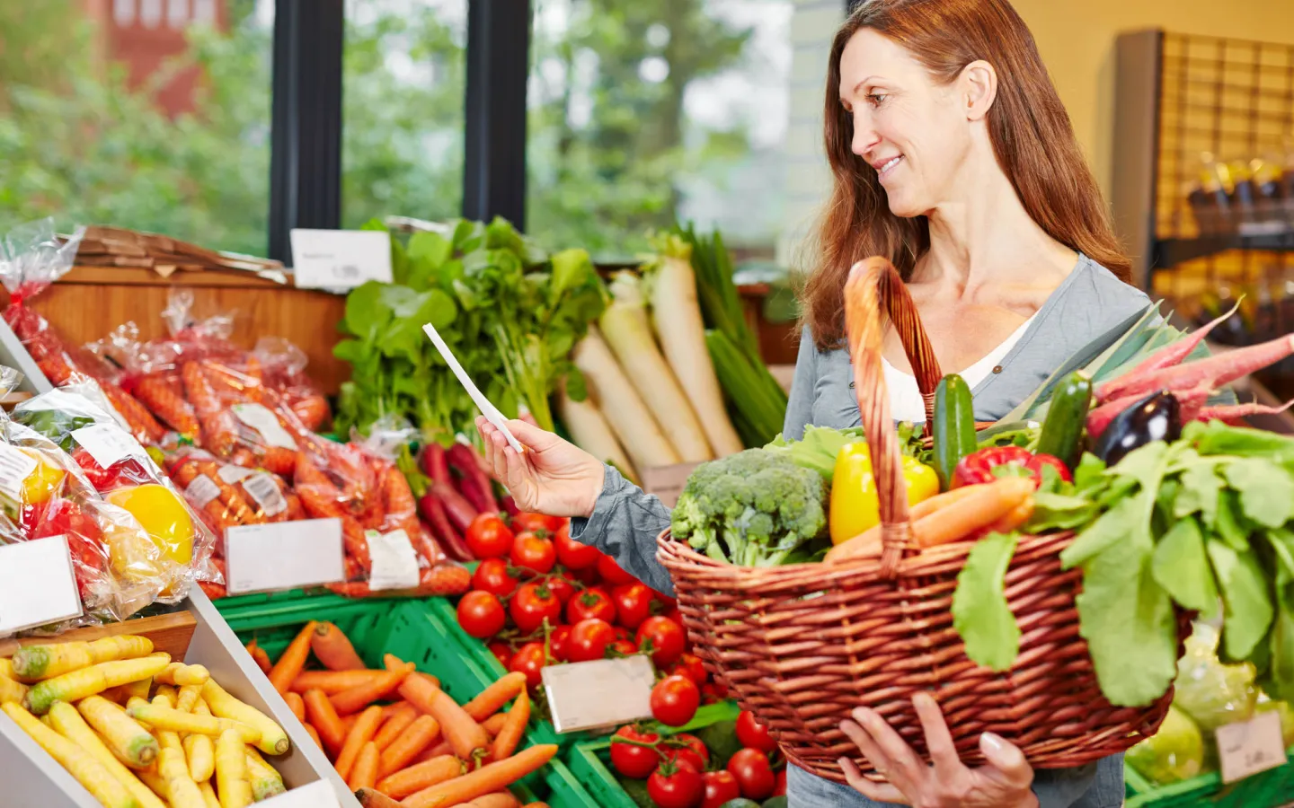 Woman with shopping bag buys vegetables